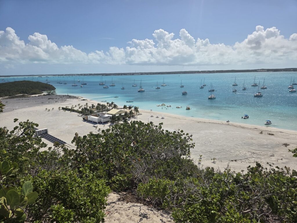 White beach curving along a harbor full of anchored boats