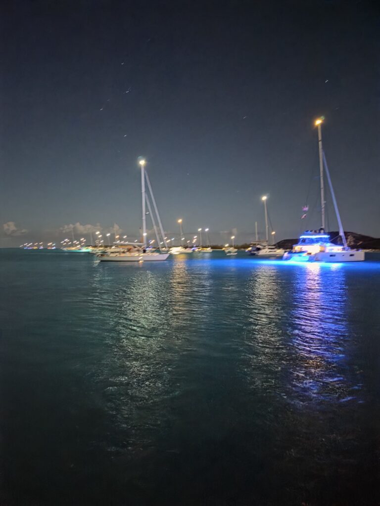 Anchor lights of boats reflected on dark water at dusk